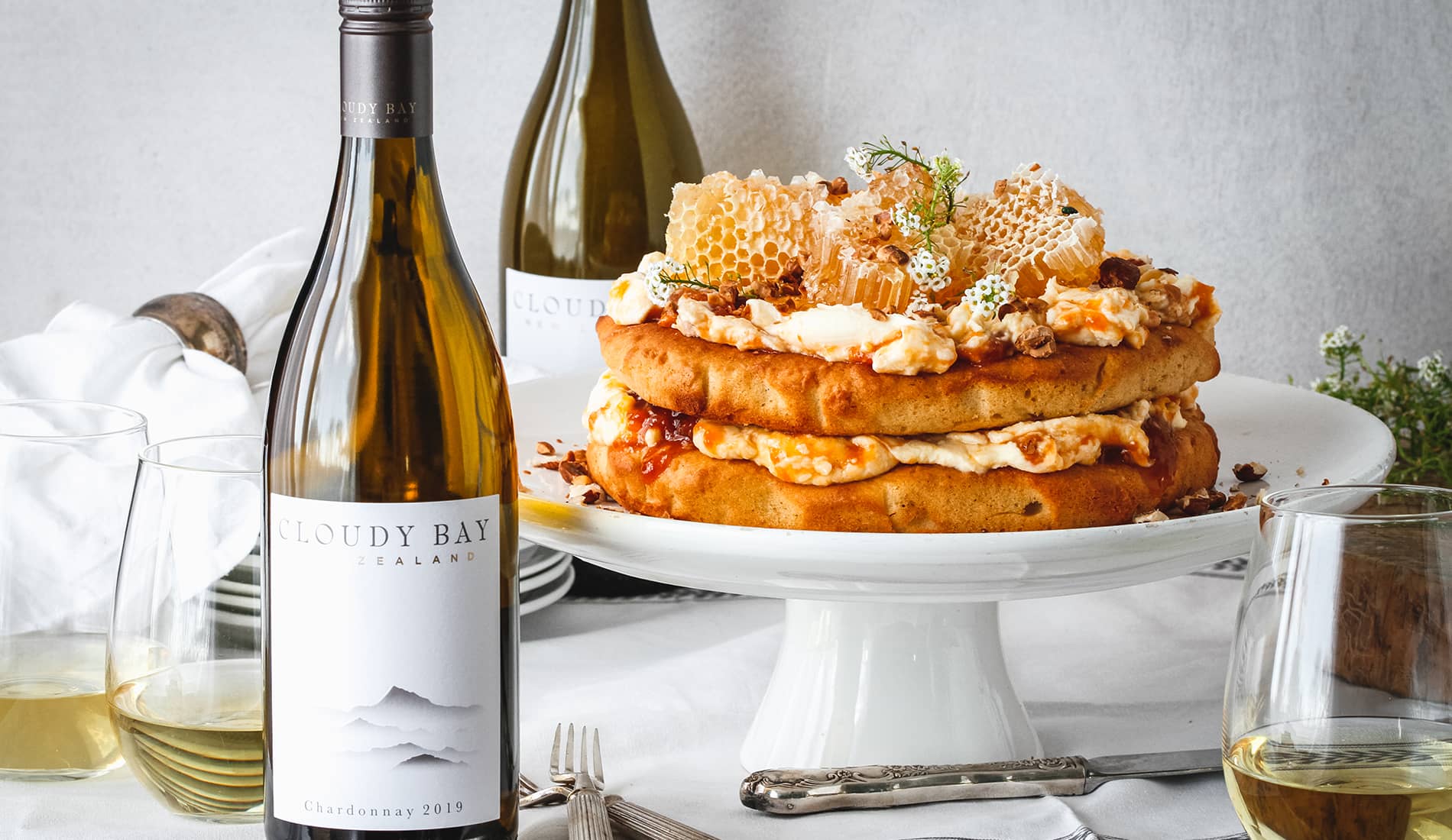 Layered ckae beside bottle and glass of Cloudy Bay Chardonnay